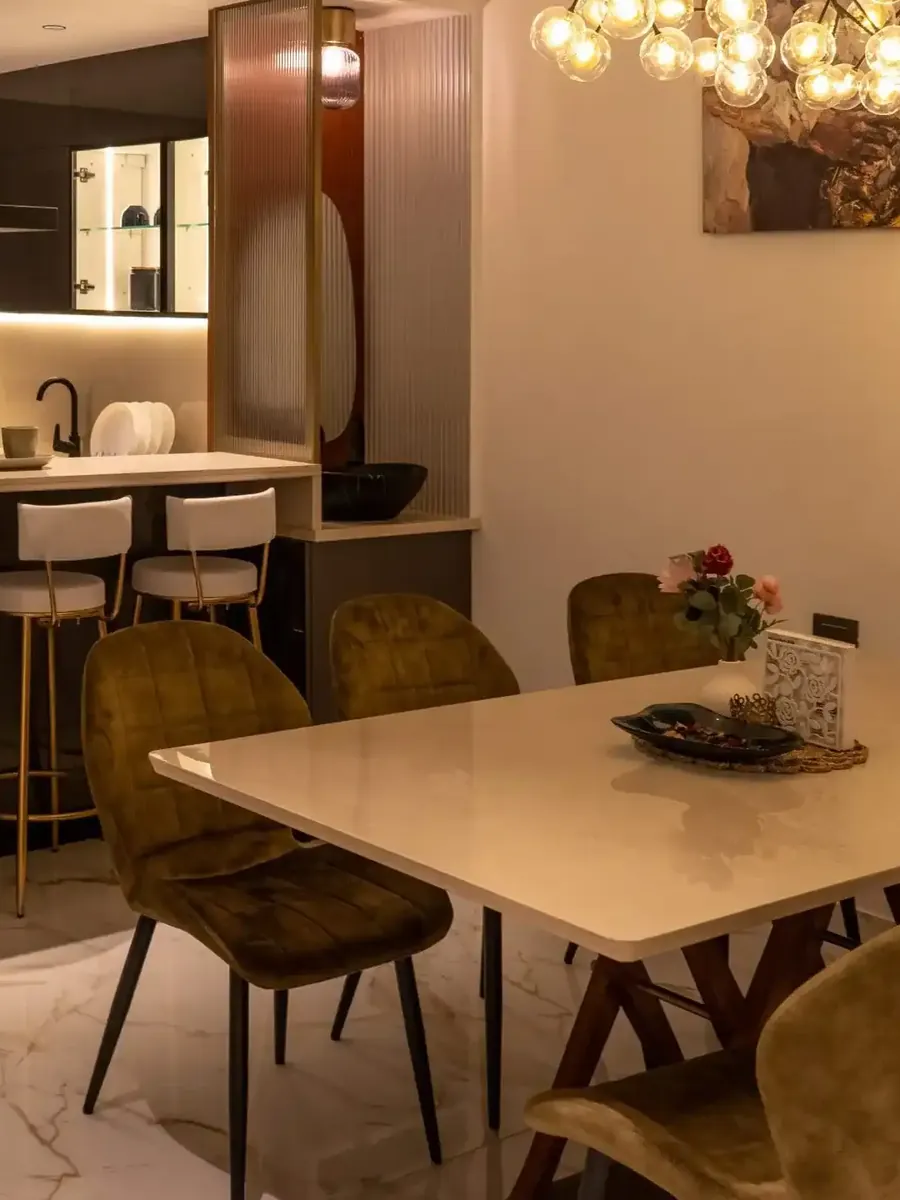 Elegance by Guru Punvaanii, Bidadi, show villa A dining table with upholstered chairs beside an open kitchen in the Elegance show villa