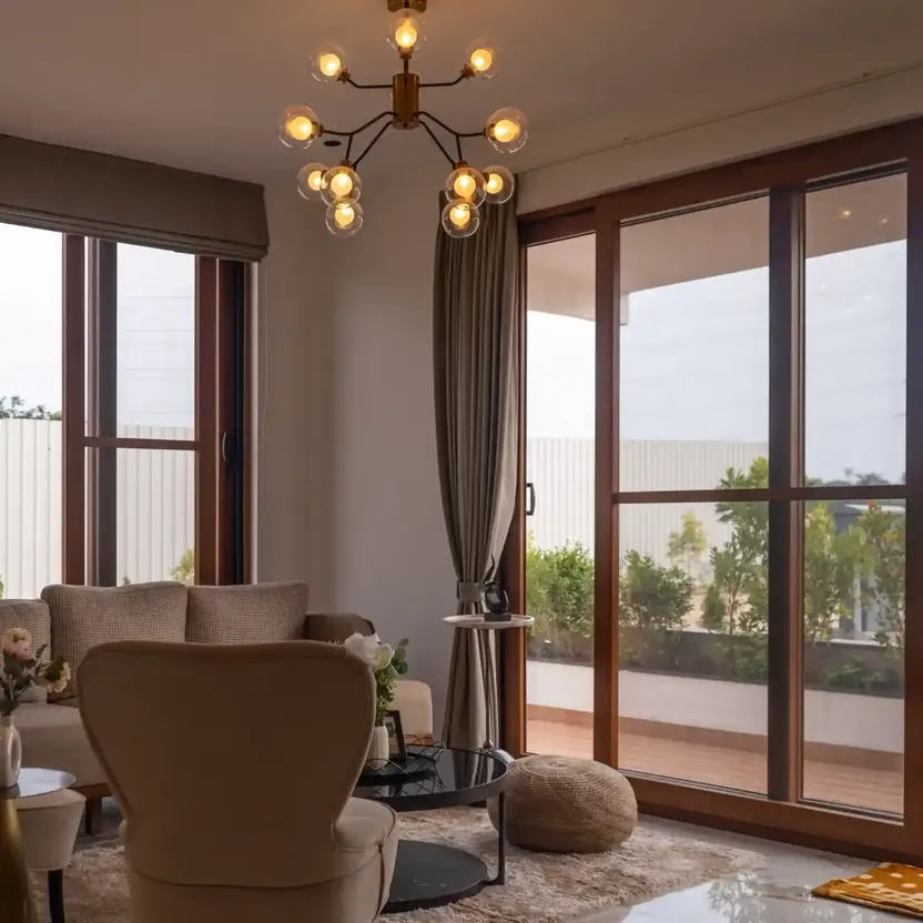 Elegance by Guru Punvaanii, Bidadi, show villa A sitting room with tall windows, armchairs and a chandelier in the Elegance show villa